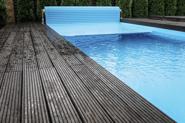 Piscine avec couverture automatique et terrasse en bois.