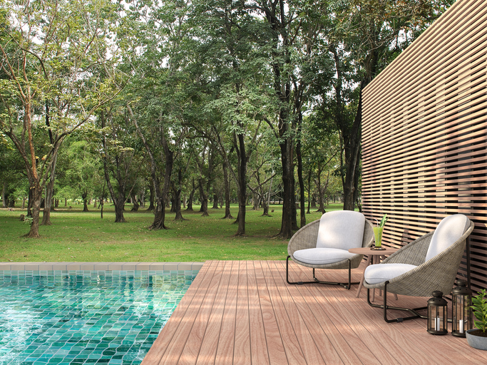 Deux fauteuils de jardin sur une terrasse en bois, au bord d'une piscine carrelée.