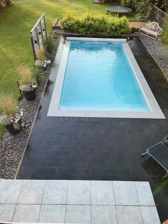 Piscine à fond plat entourée d'une margelle en grès cérame réalisée pour un client à Verlaine.